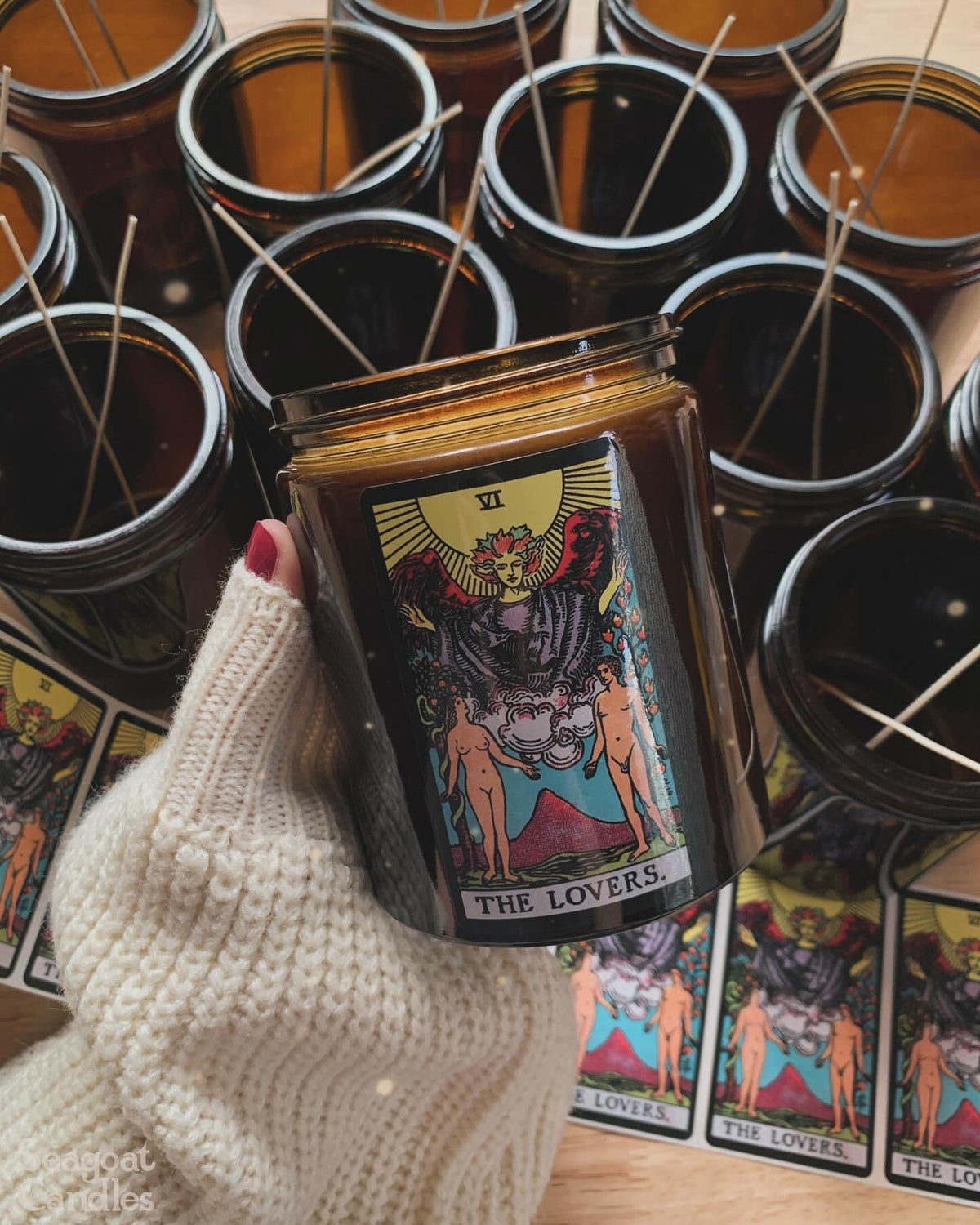 Candle with 'The Lovers' tarot card design surrounded by more candles and tarot cards.